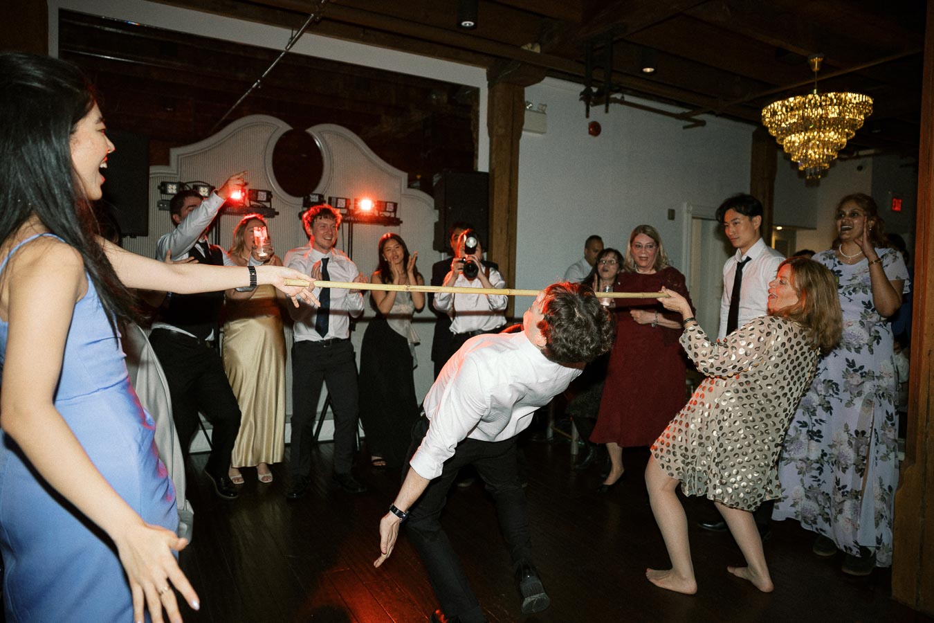 Guests laughing and cheering as a man plays limbo on a dance floor
