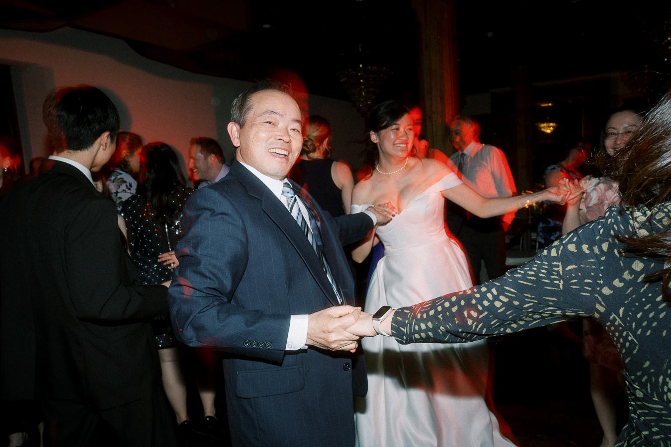 Guests dancing and holding hands at a lively indoor reception