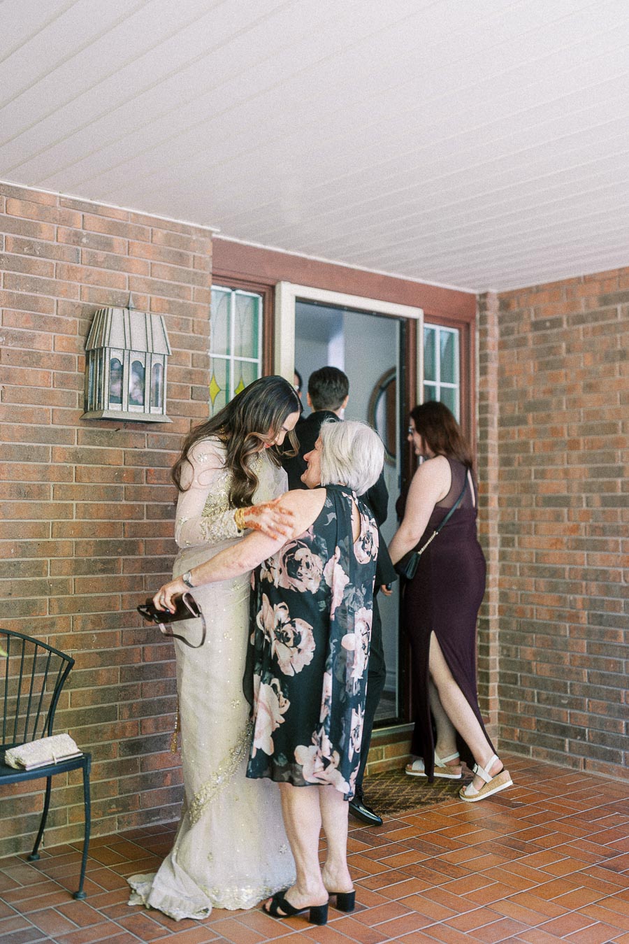 Family gathering at a home entrance, with people warmly greeting one another on a brick patio with a welcoming atmosphere.