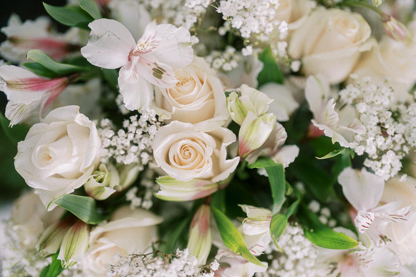 A beautiful bouquet featuring white roses, delicate baby's breath, and soft pink alstroemeria flowers, creating an elegant and romantic floral arrangement.