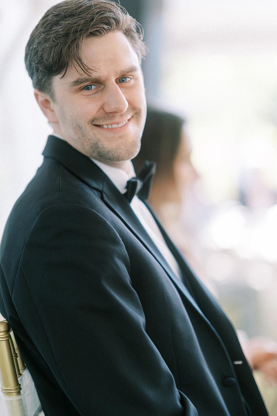 Smiling man in formal black tuxedo at a wedding event.