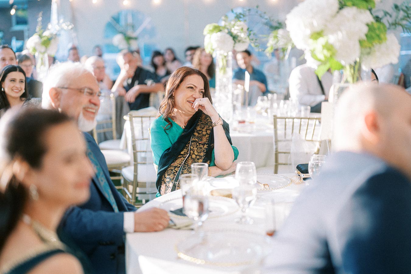 Guests enjoying a joyful moment at a beautifully decorated wedding reception, adorned with flowers and elegant table settings, capturing a festive atmosphere.