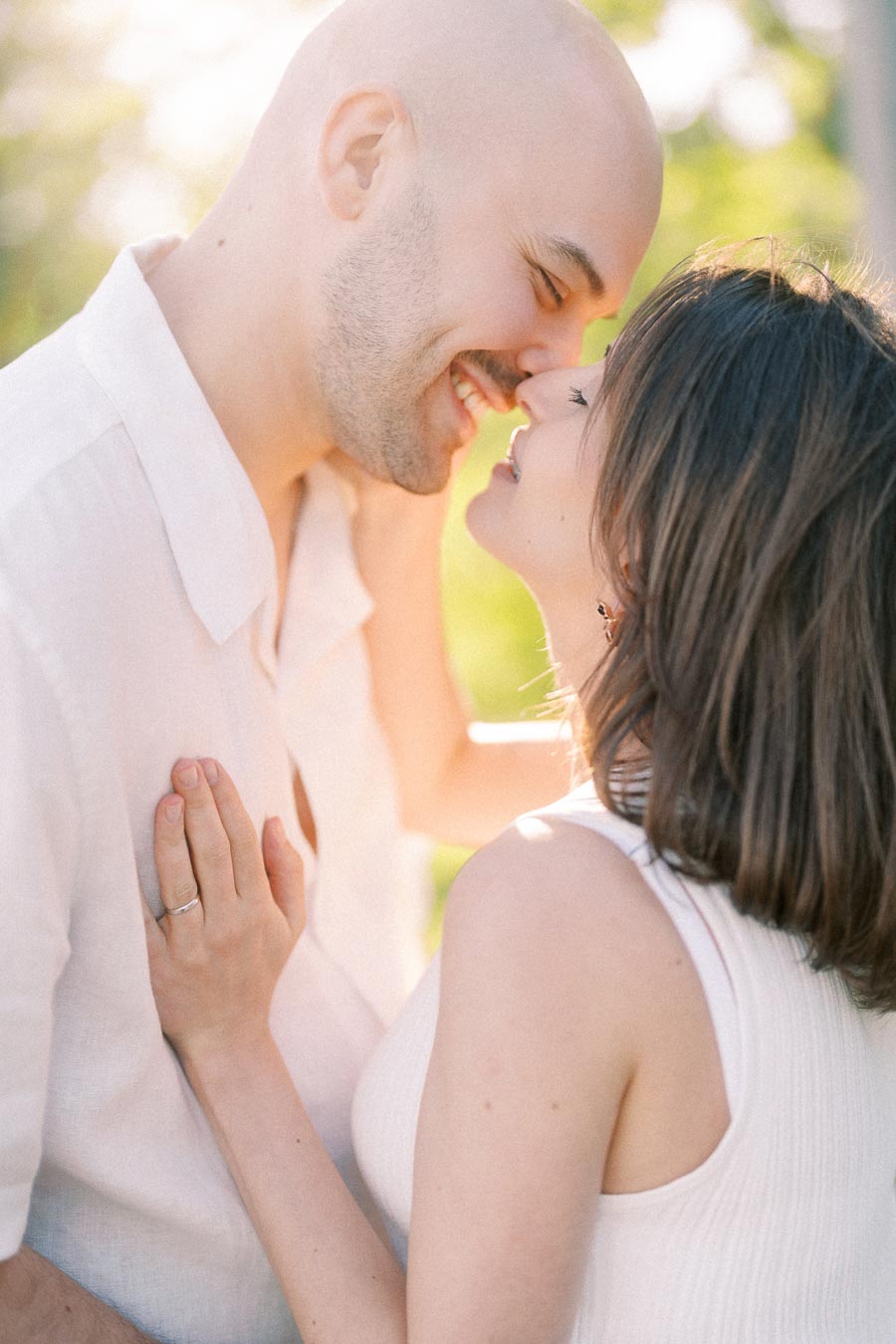 Close-up of a couple smiling with their noses touching in warm outdoor light.