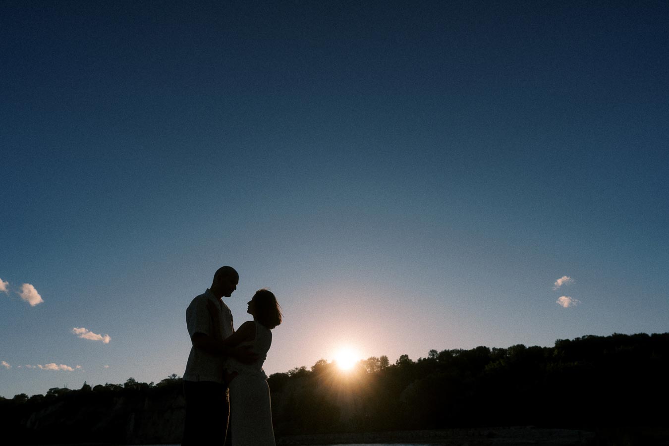 Silhouetted expectant couple standing together at sunset near the Scarborough Bluffs shoreline.
