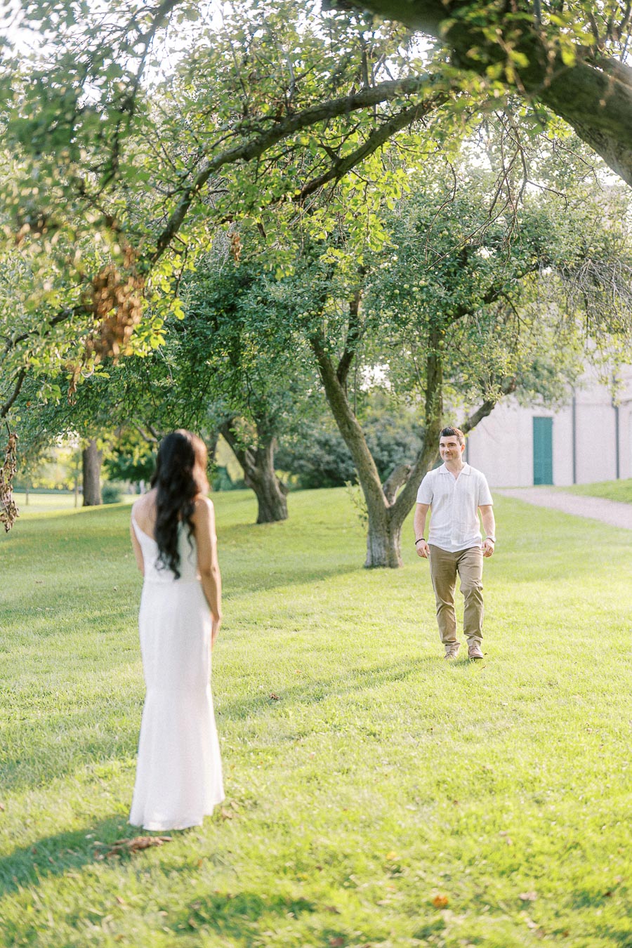 Couple walking toward each other beneath trees at Dundurn Castle in Hamilton