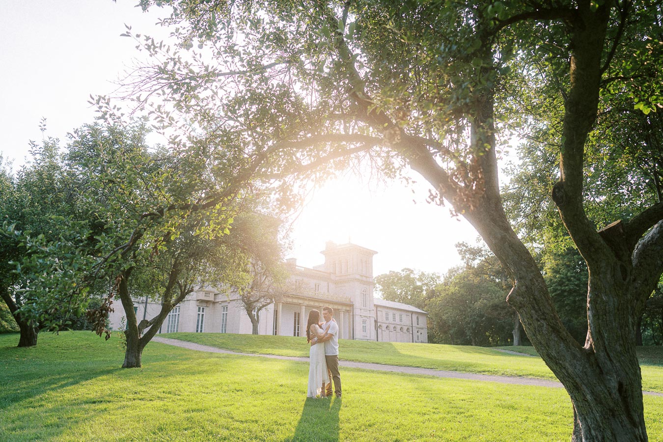 Couple embracing on Dundurn Castle lawn framed by sunlit trees