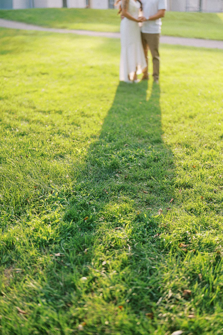 Long shadows of an engaged couple on grass at Dundurn Castle