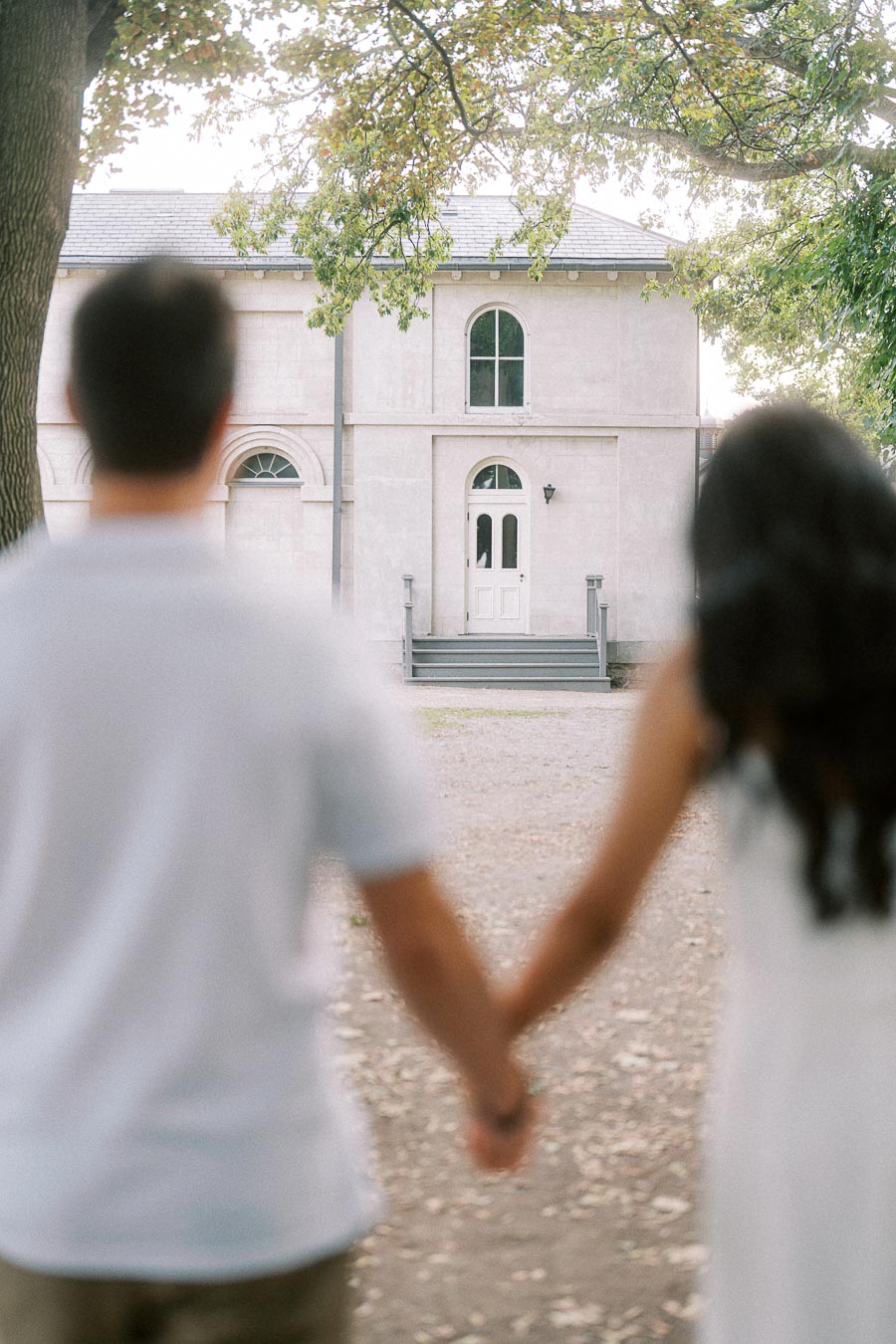 Couple holding hands facing Dundurn Castle outbuilding in Hamilton