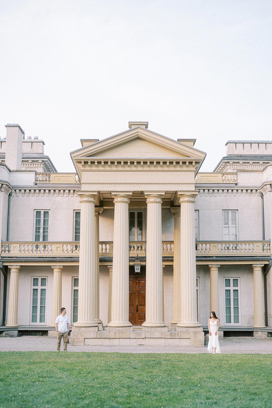 Couple standing apart before Dundurn Castle columns in Hamilton