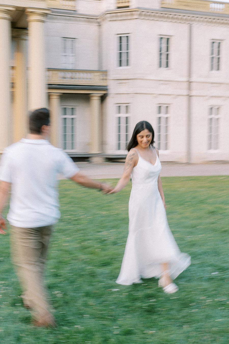 Couple holding hands on lawn during Dundurn Castle engagement photoshoot