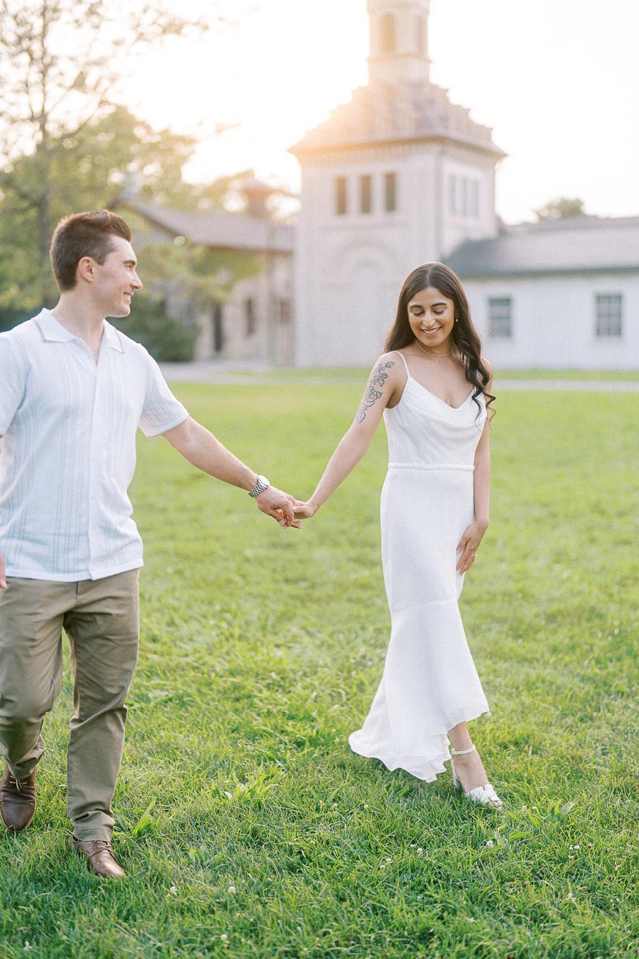 Engaged couple holding hands on Dundurn Castle lawn in Hamilton