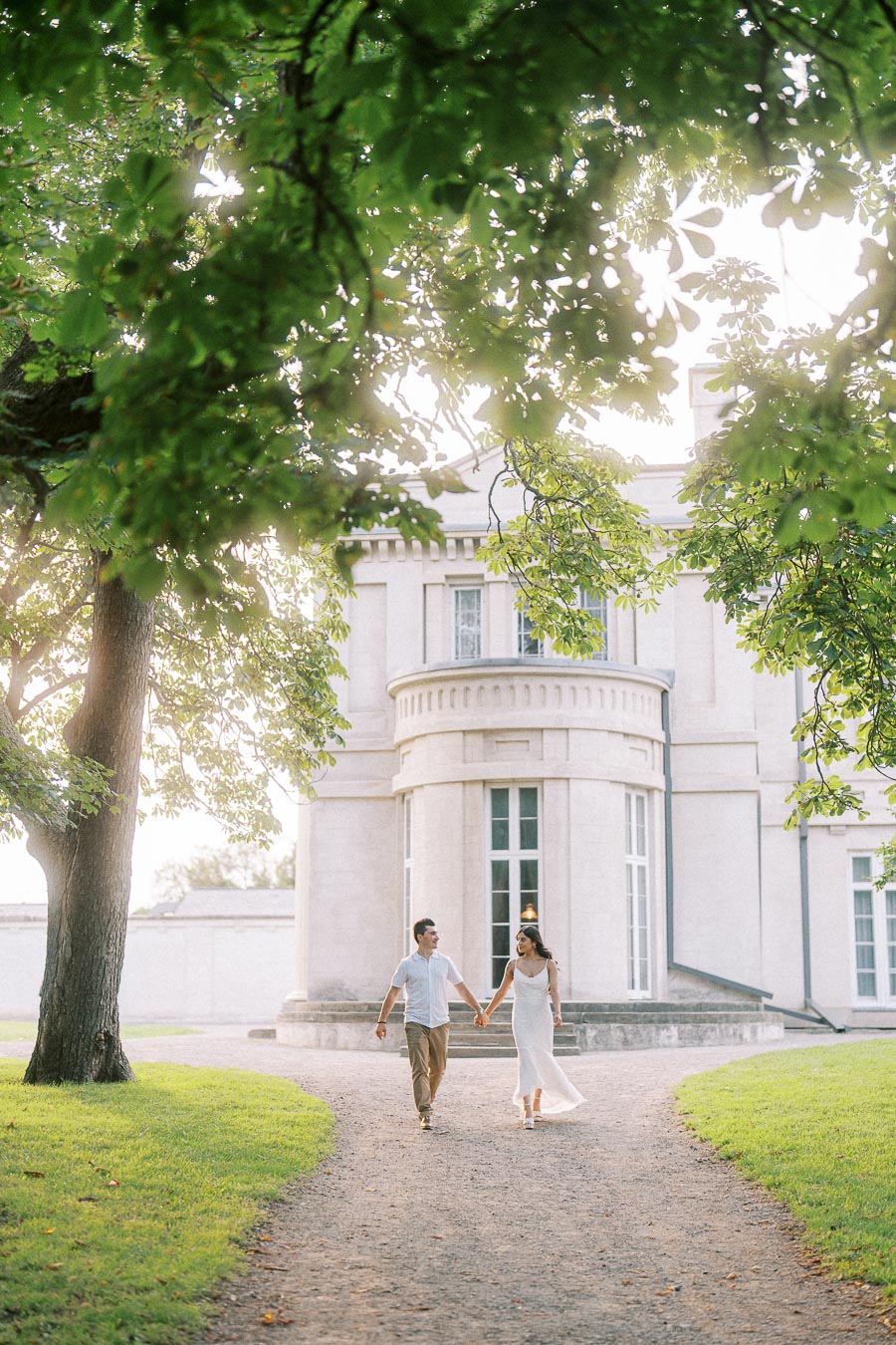 Couple holding hands on Dundurn Castle pathway beneath leafy trees