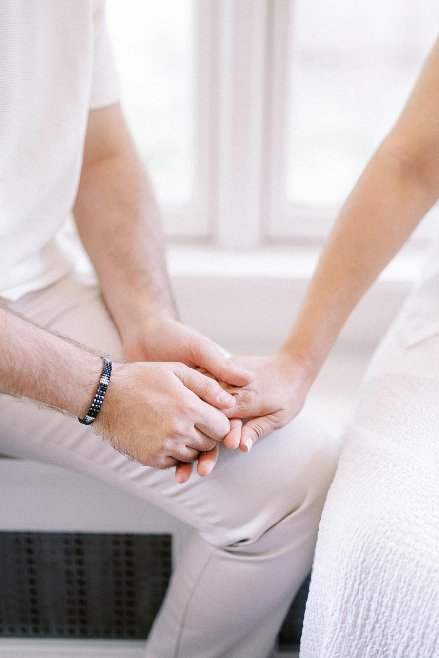 Couple holding hands while seated together in a bright indoor setting.
