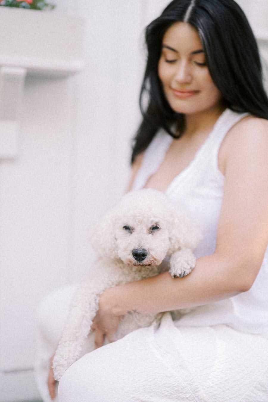 Woman in a white dress holding a small white dog.