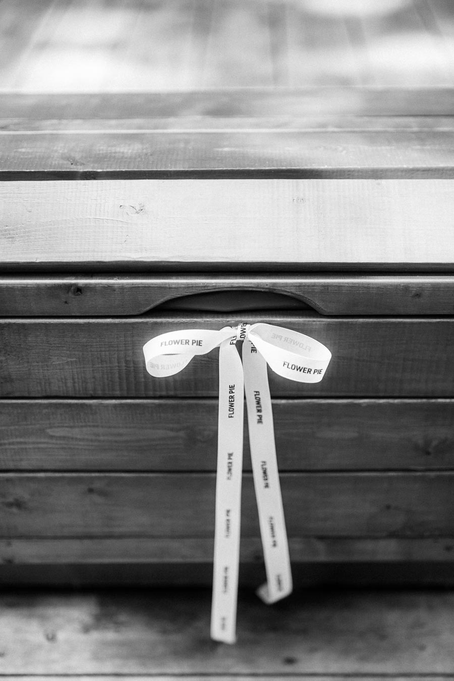Black and white detail of a Flower Pie ribbon tied to a wooden bench.
