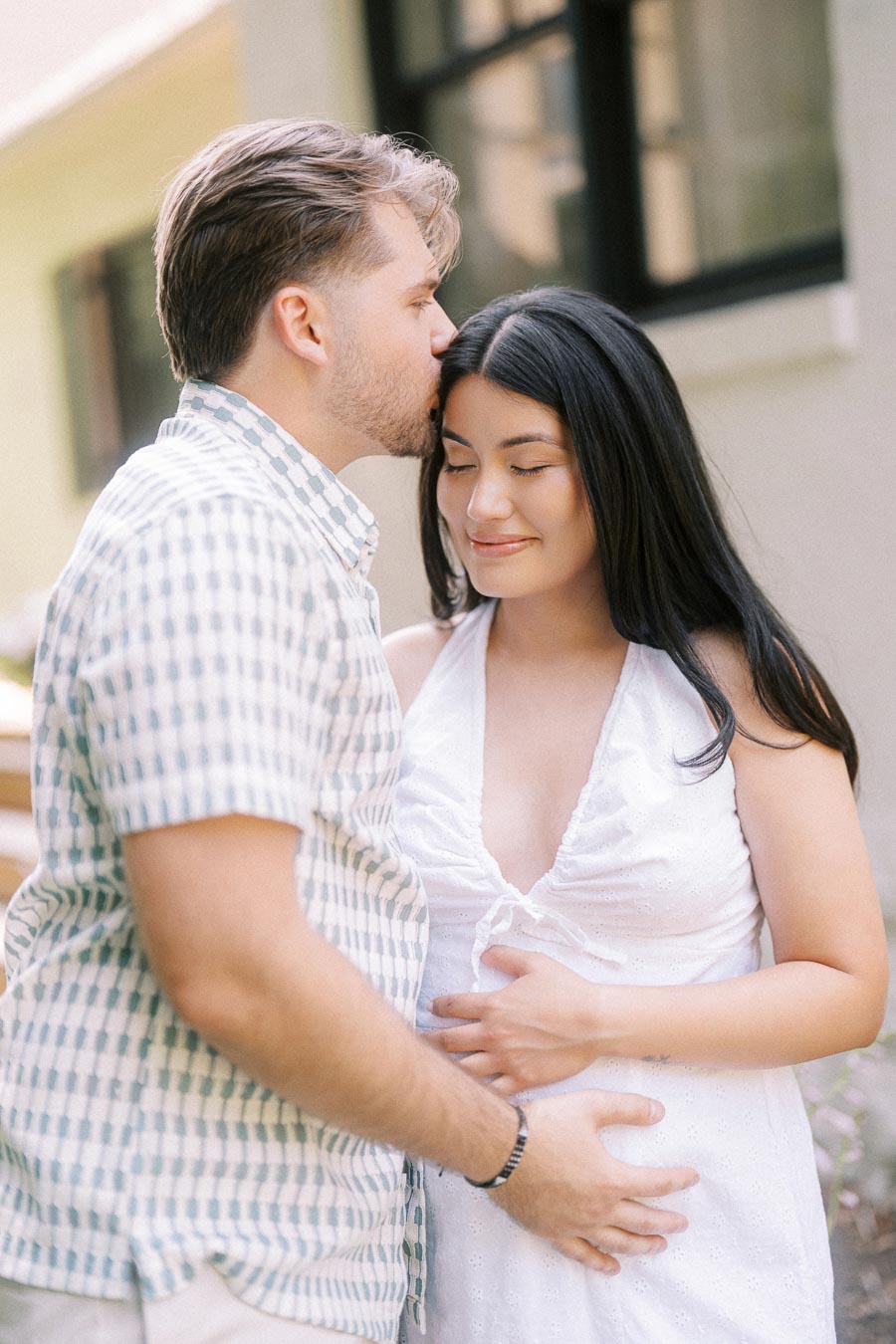 Man kisses woman's forehead during a tender Toronto engagement photo.