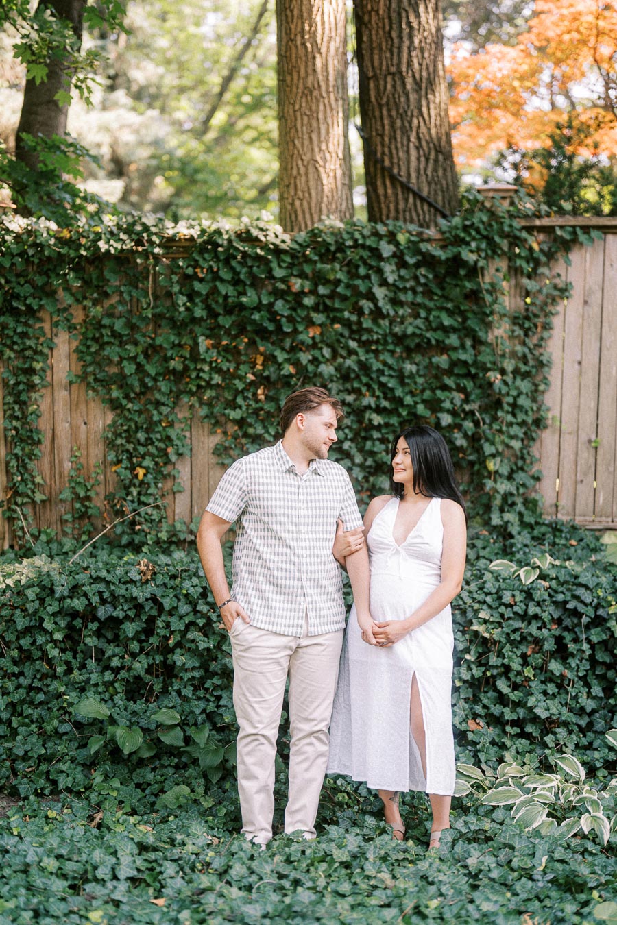 Couple standing together in a leafy garden during a Toronto engagement photo.