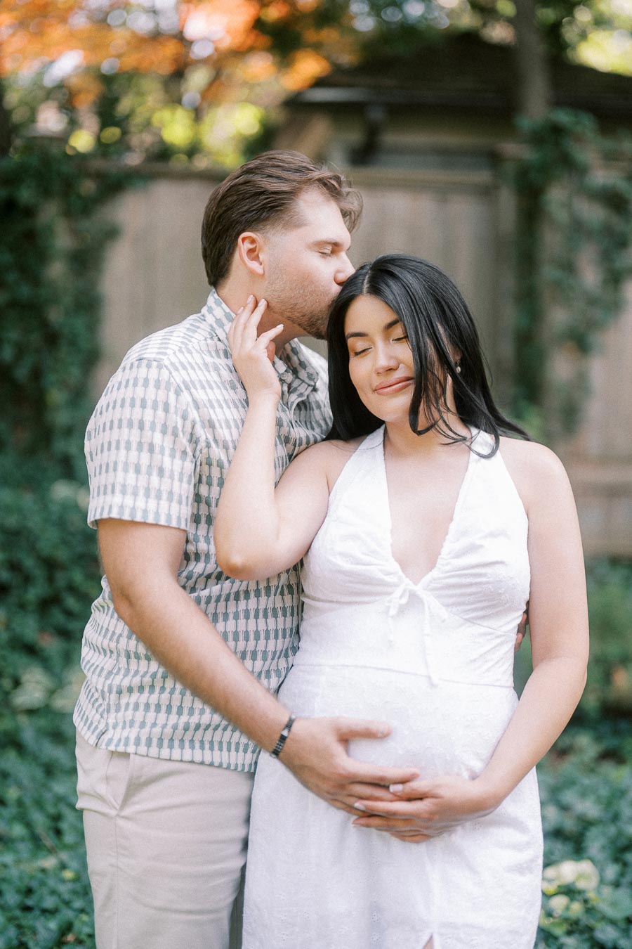 Expectant couple embracing in a garden during a Toronto engagement photo.