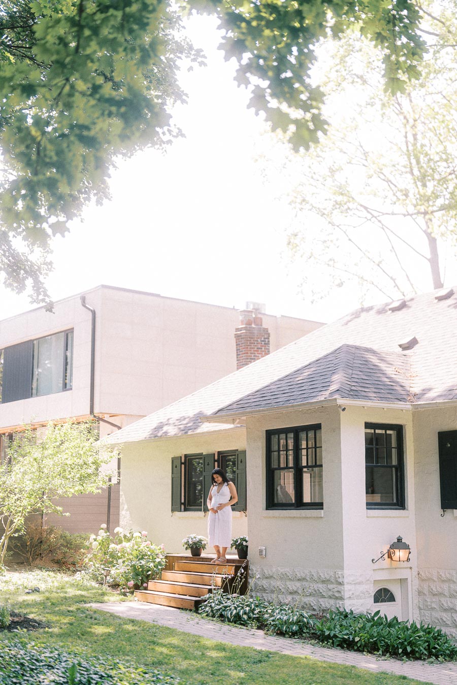 Woman in a white dress standing on the steps of a Toronto home.
