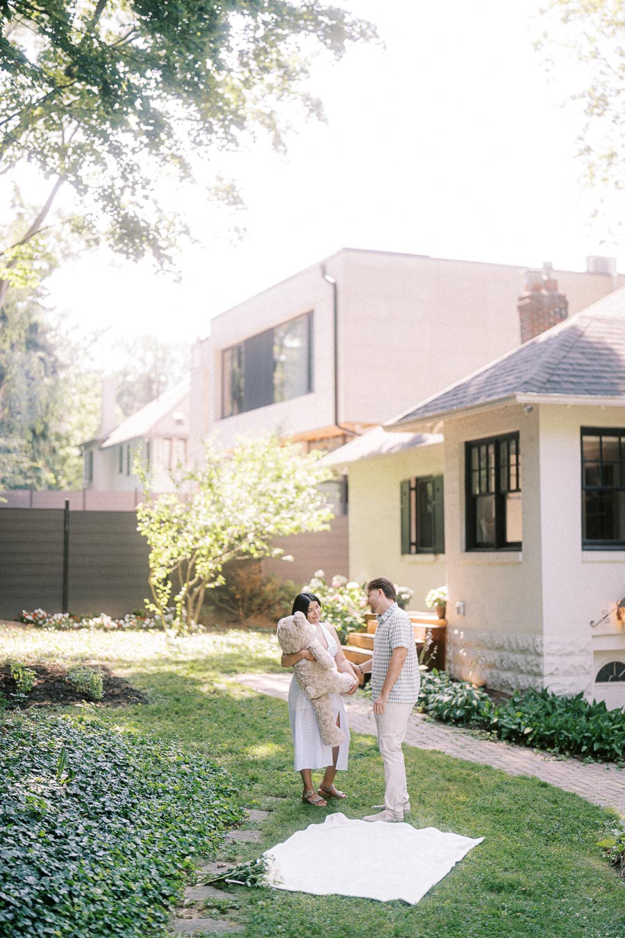 Couple standing in a sunny backyard garden during a Toronto engagement photo.