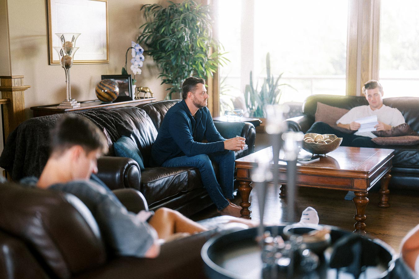 Men relaxing on leather sofas in a bright living room before an engagement photoshoot