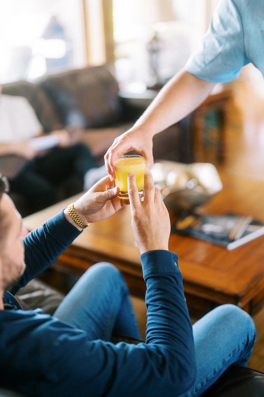 Person in a navy shirt receives a yellow drink during an indoor engagement session.