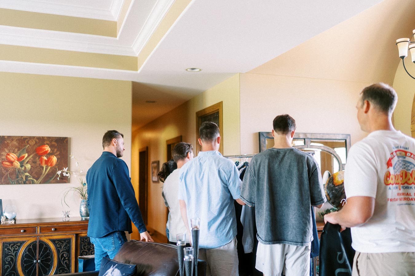 Group of men choosing clothes indoors during pre-wedding preparations at home.