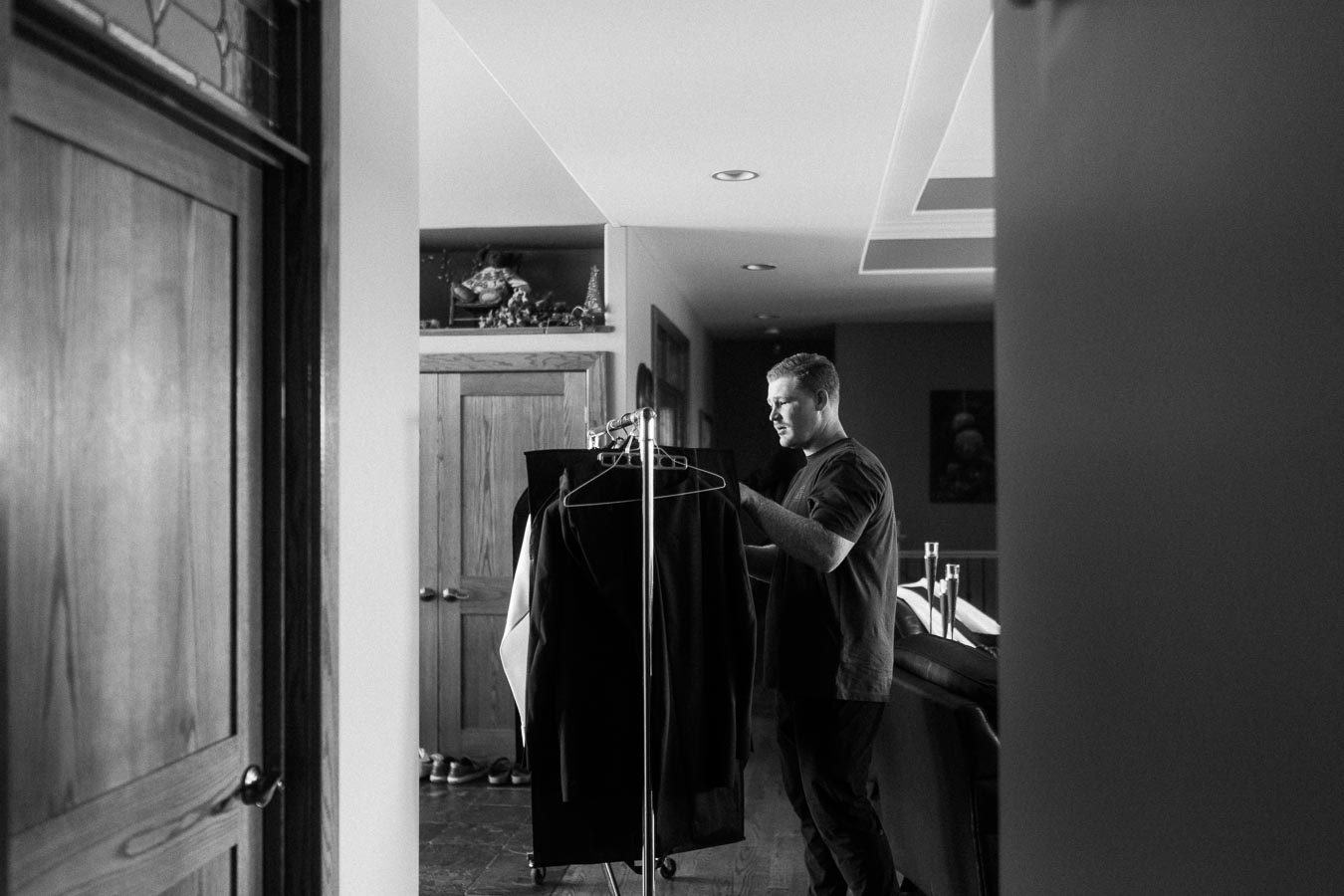 Man selecting clothes from a garment rack in a home hallway