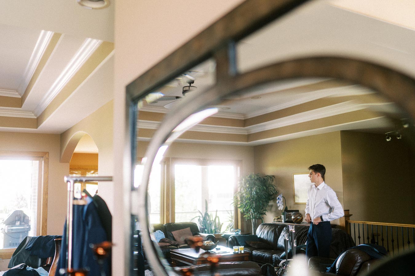 Man in a white shirt getting ready in a sunlit living room before an engagement session