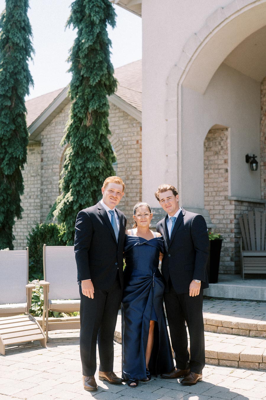 Groom with mother and brother posing outside a brick family home near Chatham-Kent, Ontario before a wedding.