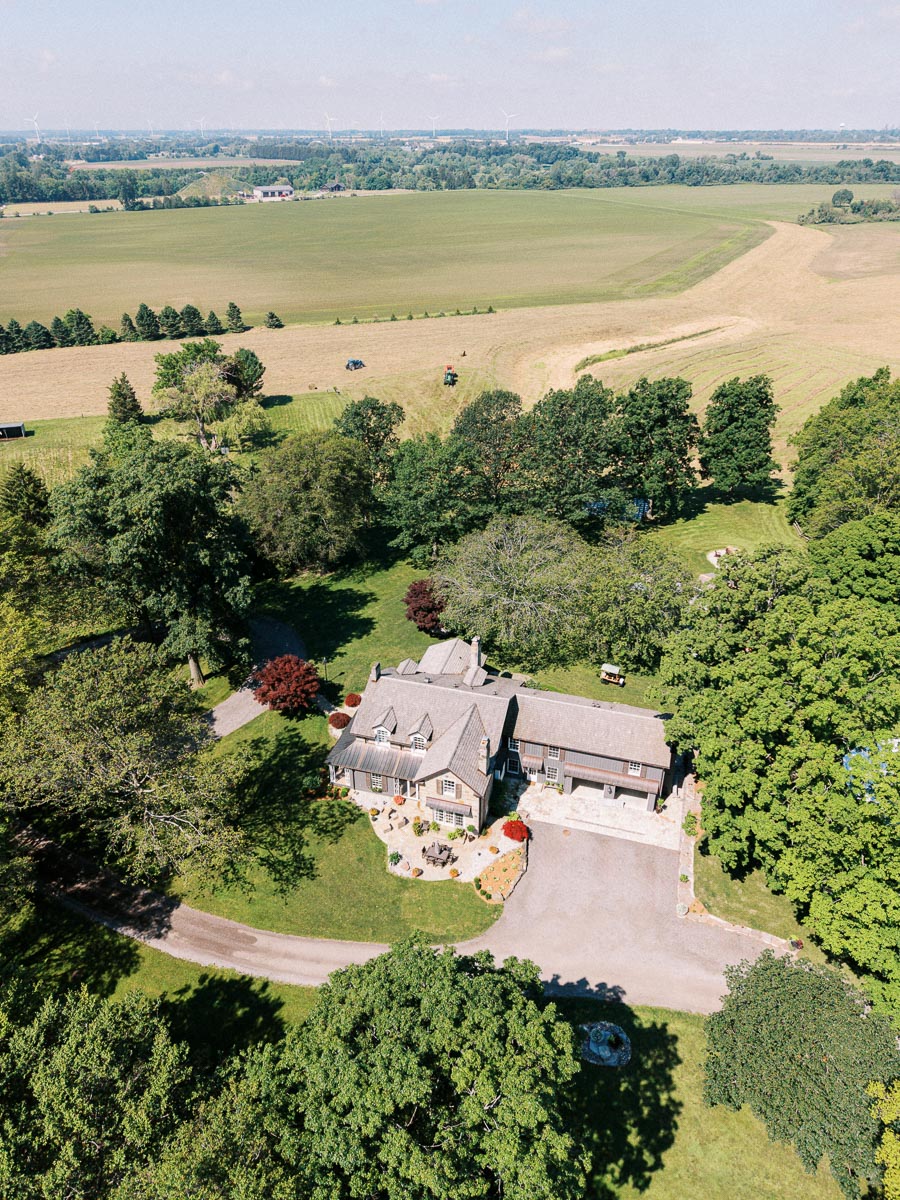 Aerial view of a private farm estate with a large house, driveway, trees, lawns, and surrounding crop fields near Chatham-Kent, Ontario.