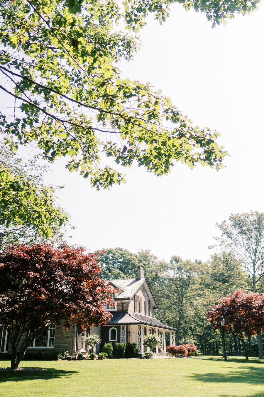 Historic stone farmhouse on a green lawn surrounded by maple trees near Chatham-Kent, Ontario, Canada.