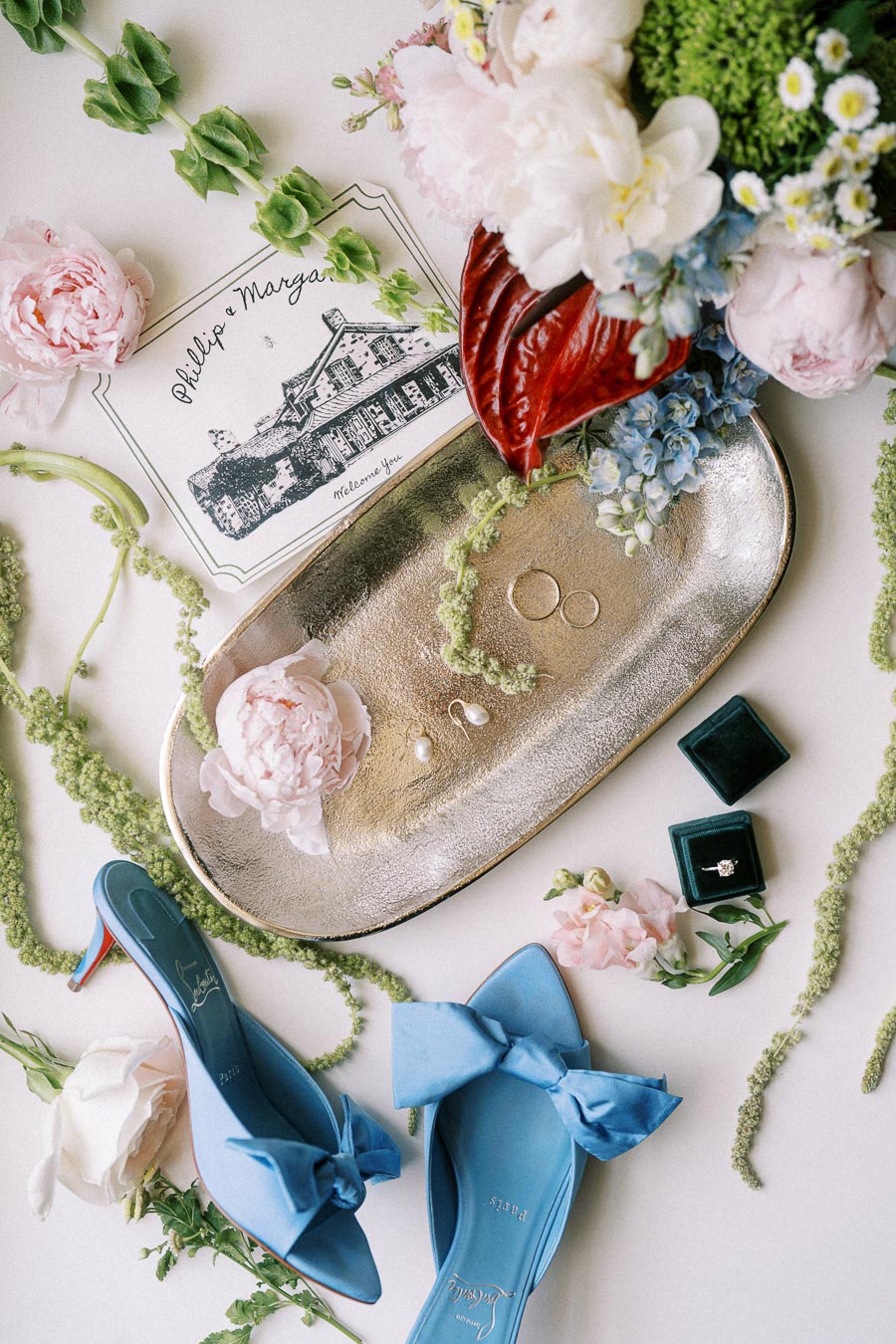 Flat lay of bridal details with blue heels, rings, invitation card, flowers, and gold tray for an Ontario farm wedding near Chatham-Kent.