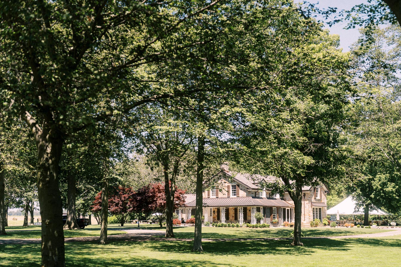 Private estate wedding venue on a farm near Chatham-Kent, Ontario, with a large house, lawn, trees, and white reception tent.