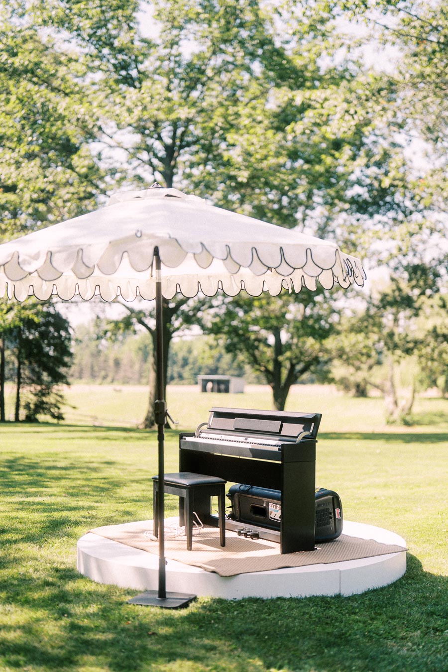 Outdoor piano setup under a white umbrella on a green lawn at a private farm estate near Chatham-Kent, Ontario.