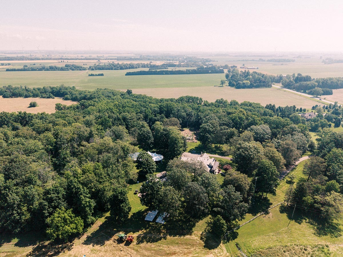 Aerial view of a private farm estate with trees, fields, lawn, tents and rural roads near Chatham-Kent, Ontario, Canada.