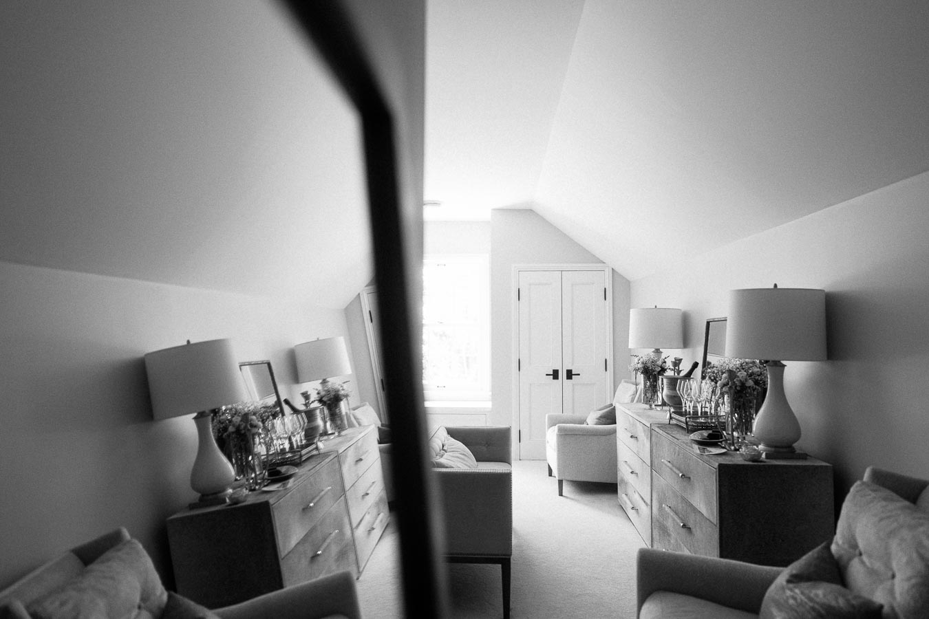 Black and white bridal getting ready room in a private estate near Chatham-Kent, Ontario, with dressers, lamps, chairs, mirror, and flowers.