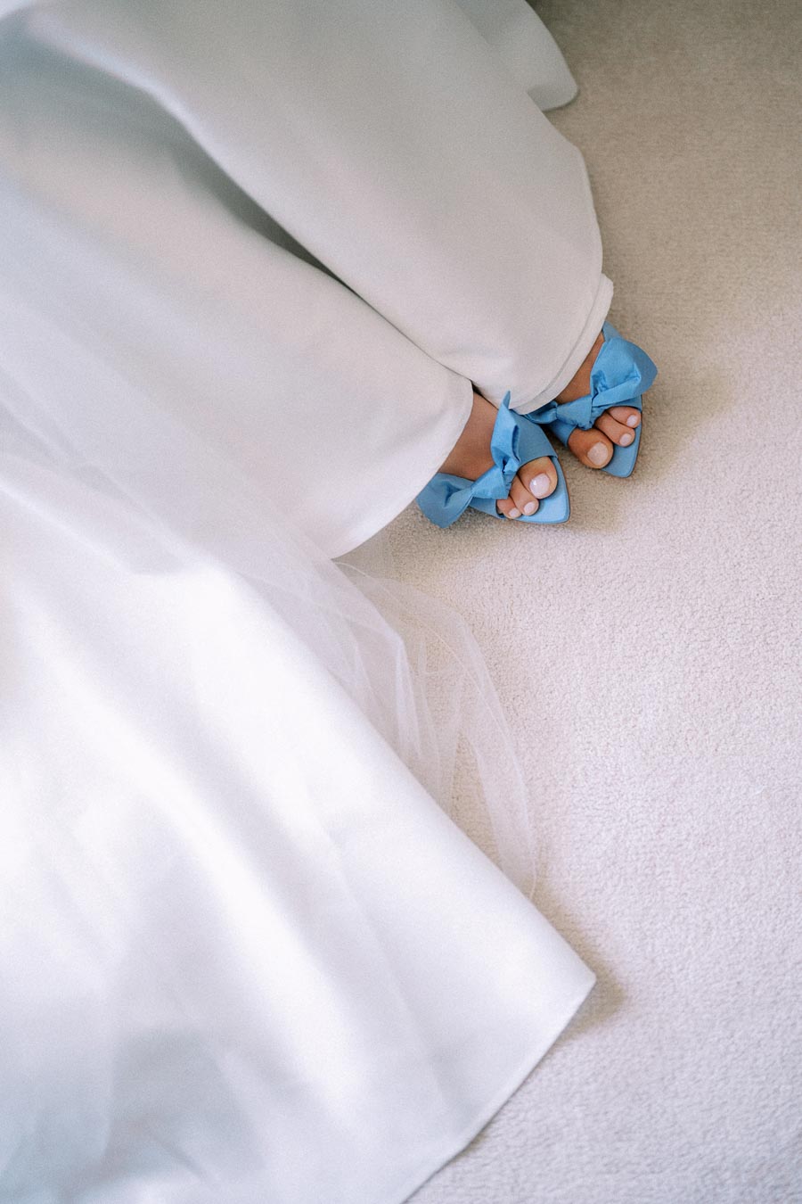 Bride wearing a white wedding dress and blue bow heels on a light carpet during wedding morning preparations in Chatham-Kent, Ontario.