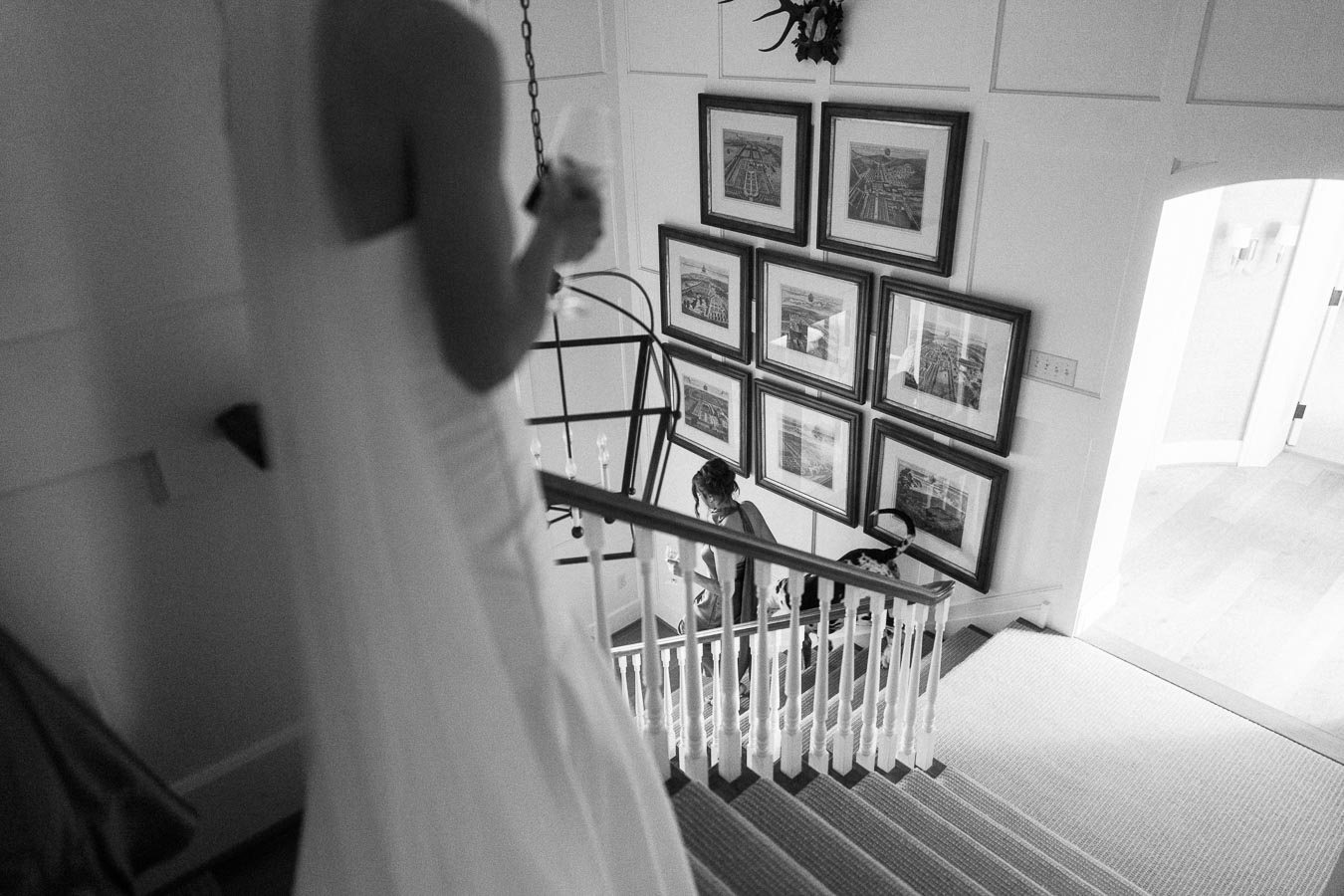 Black and white photo of a bride in a wedding dress at the top of a staircase inside a farmhouse near Chatham-Kent, Ontario.