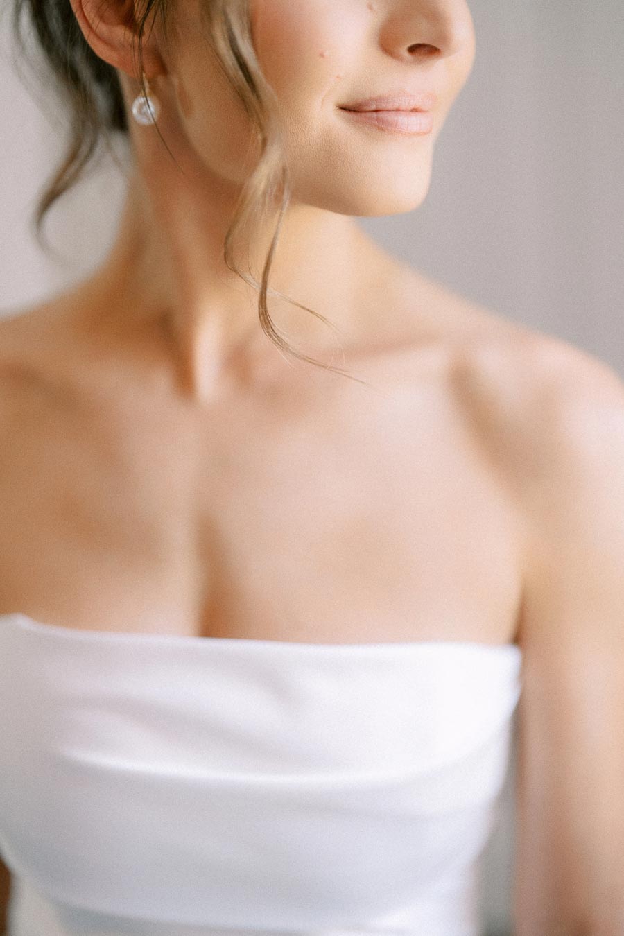 Close up portrait of a bride wearing a strapless white wedding dress and pearl earring during bridal preparations in Ontario.