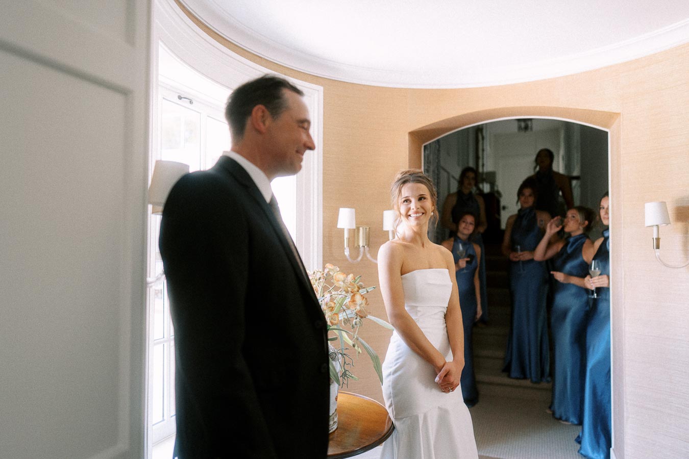 Bride in a white strapless gown smiles at her father in a black suit during a first look inside a home near Chatham-Kent, Ontario.