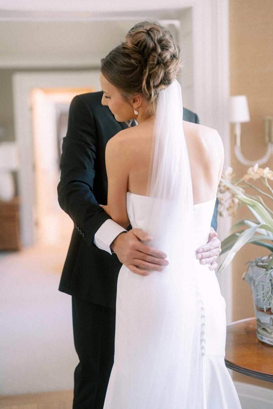 Bride in a white wedding dress and veil embraces her father in a suit during a first look inside a private home near Chatham-Kent, Ontario.
