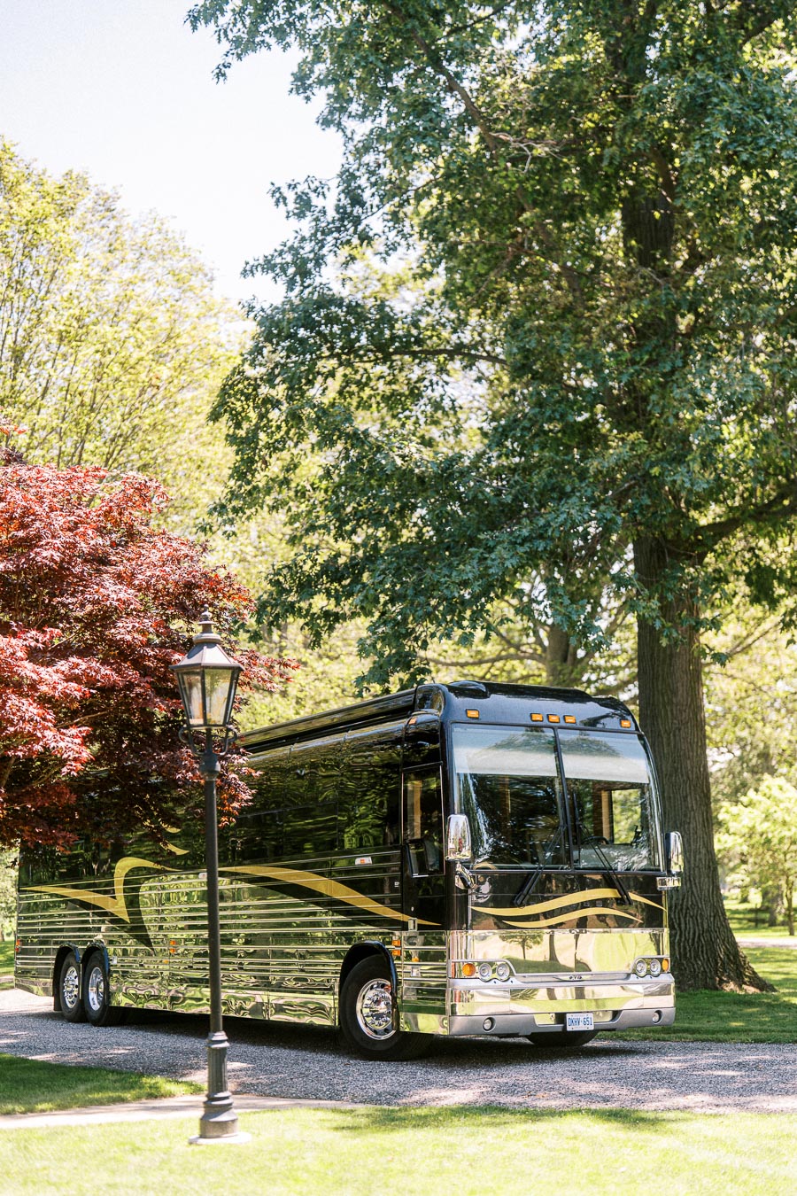 Black luxury coach bus parked on a tree lined private estate driveway near Chatham-Kent, Ontario, Canada.