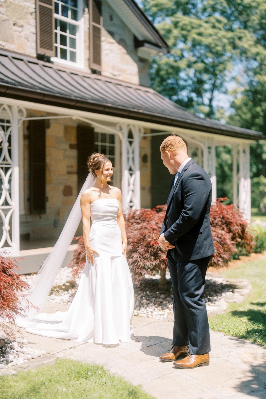 Bride and groom during a first look outside a stone private estate in Chatham-Kent, Ontario, with garden landscaping and summer sunlight.