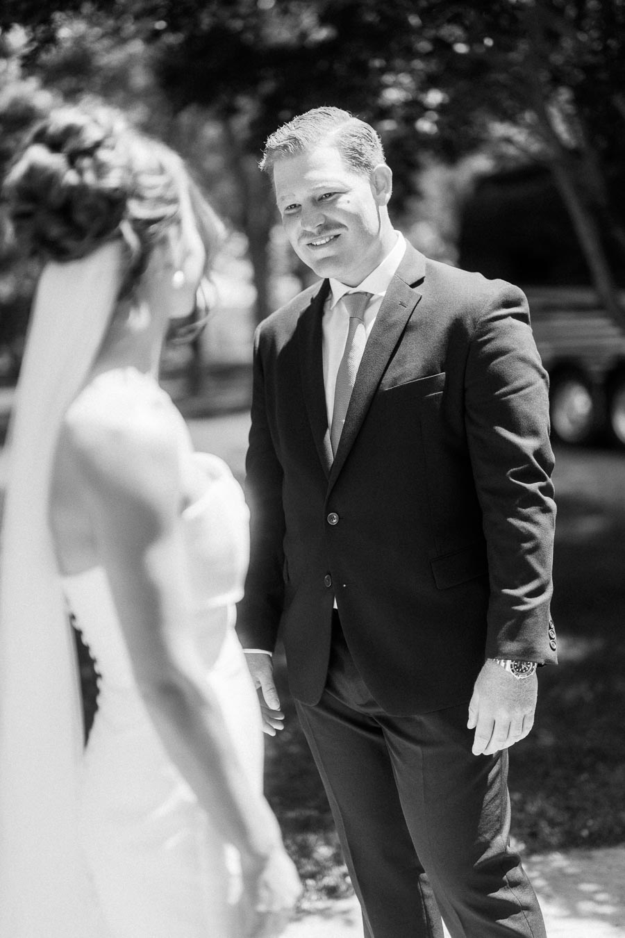 Black and white outdoor wedding first look portrait of groom smiling at bride on a private estate near Chatham-Kent, Ontario, Canada.