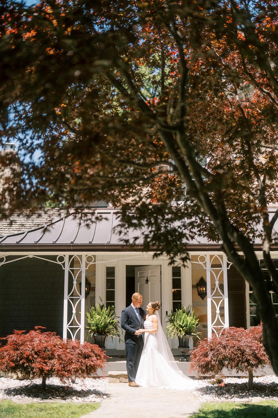 Bride and groom share a first look outside a private estate home in Chatham-Kent, Ontario, framed by Japanese maple trees and garden plants.