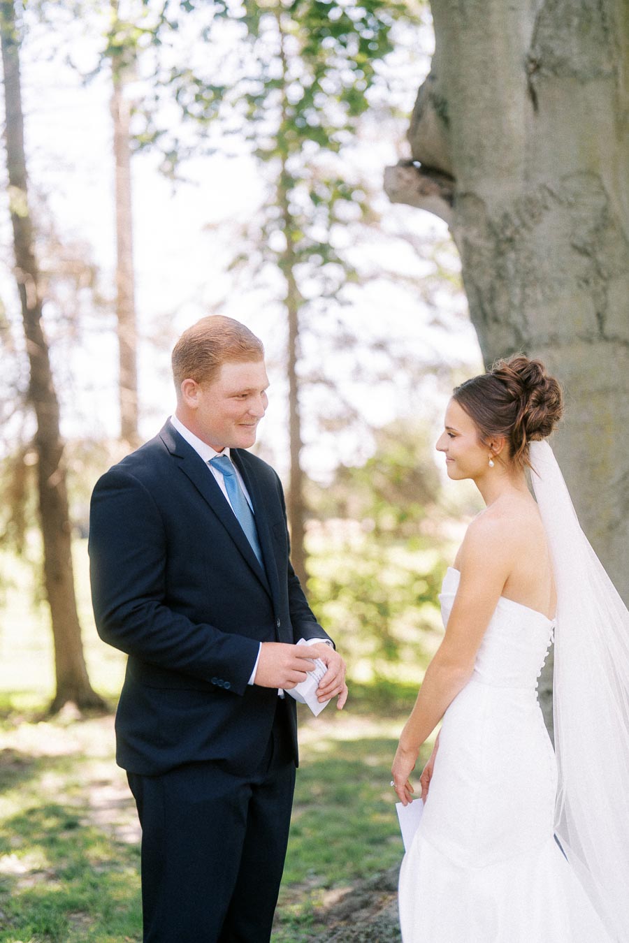 Bride and groom reading private vows under a tree before an outdoor wedding near Chatham-Kent, Ontario, Canada.