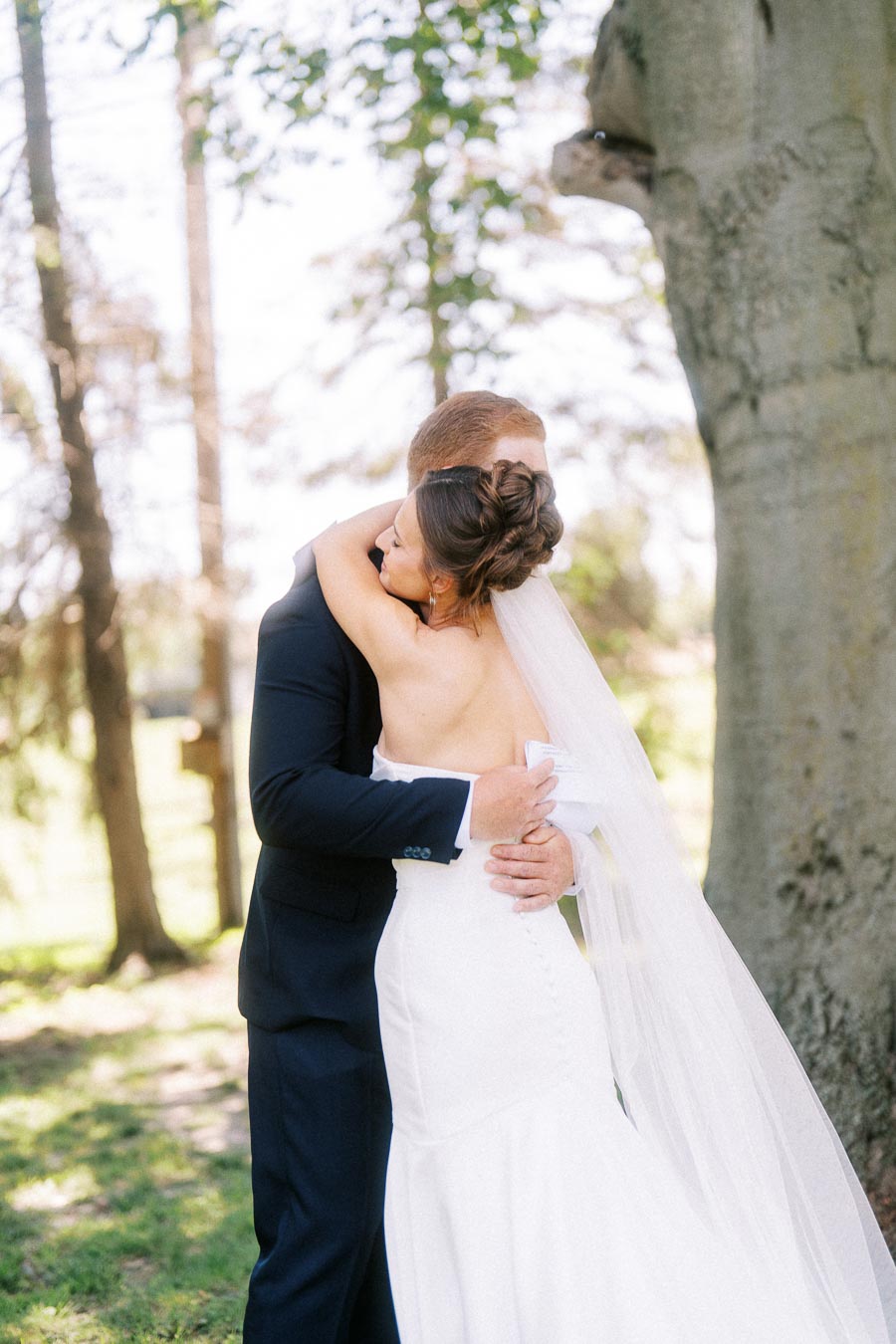 Bride and groom embracing under a large tree during an outdoor private estate wedding near Chatham-Kent, Ontario, Canada.