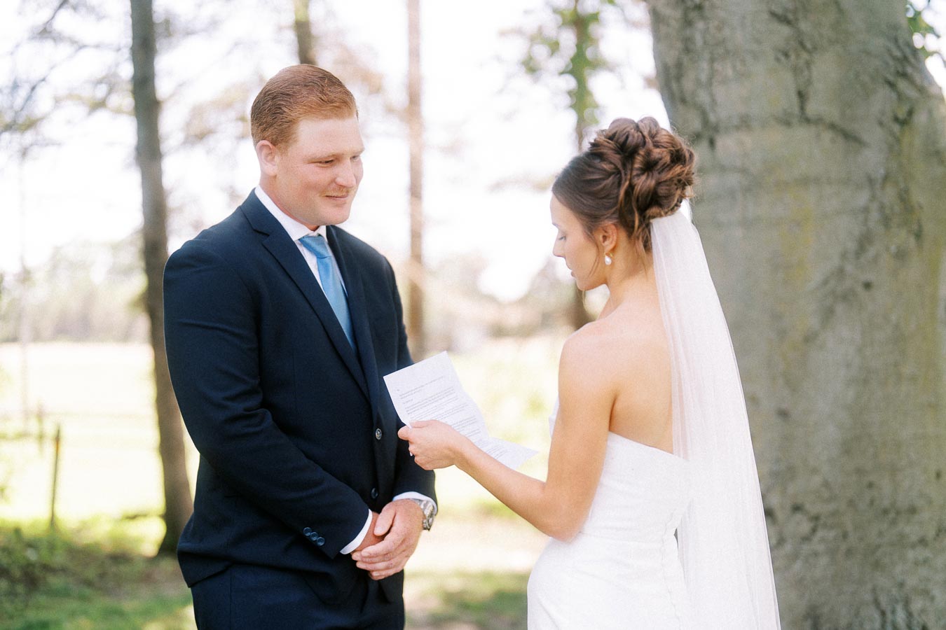 Bride reads wedding vows to groom under a large tree during an outdoor private estate wedding near Chatham-Kent, Ontario, Canada.