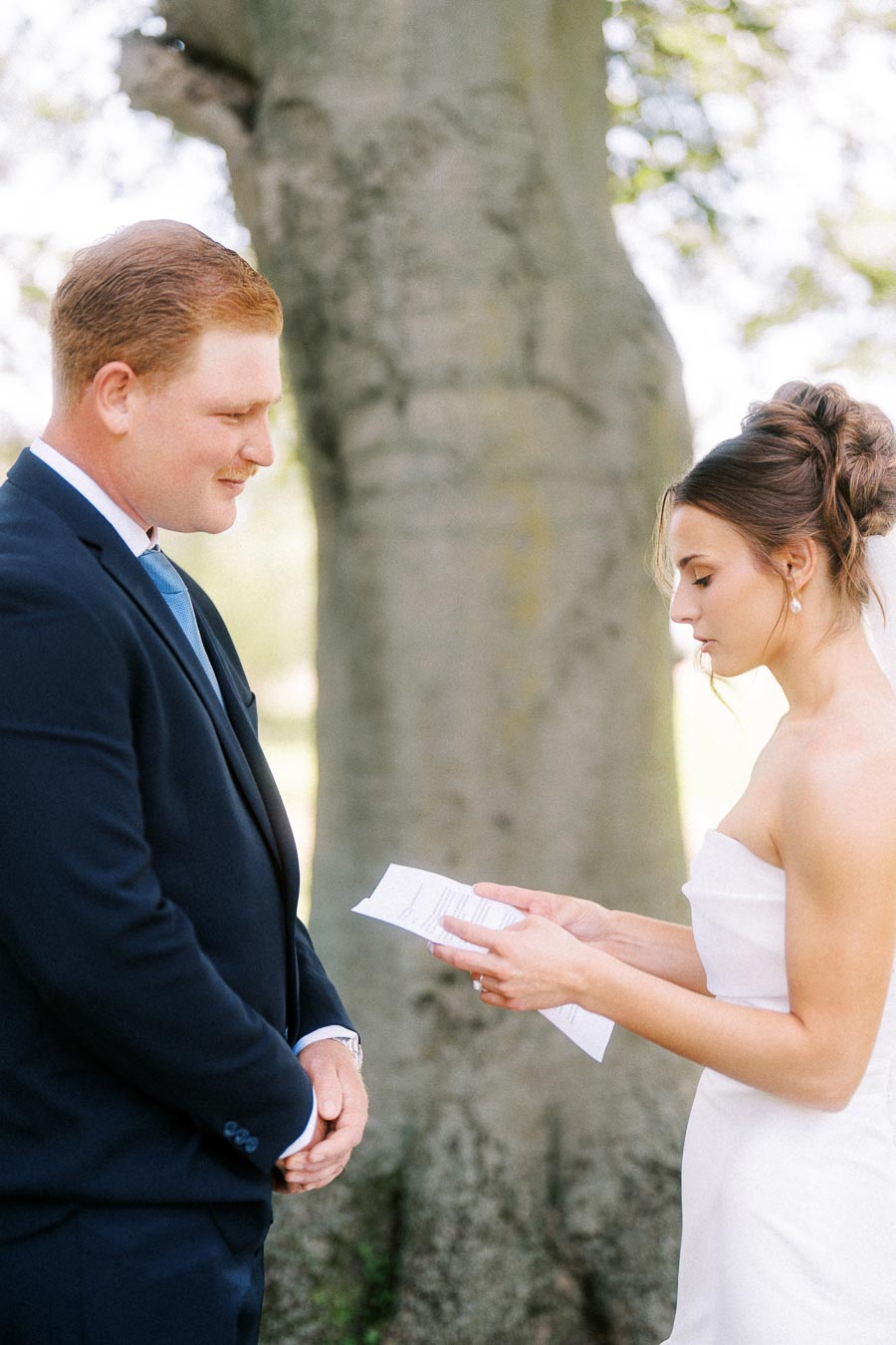 Bride and groom reading private wedding vows under a large tree near Chatham-Kent, Ontario, Canada.